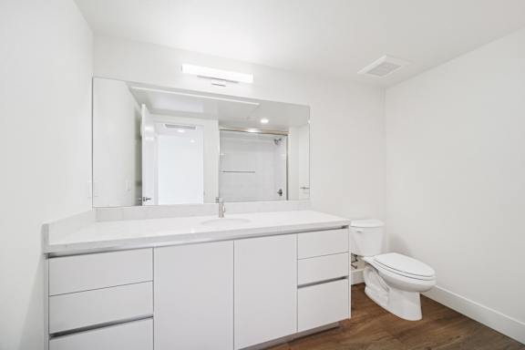A white bathroom with a toilet and a vanity with a mirror.