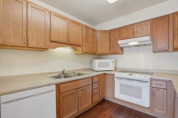 A kitchen with wooden cabinets and white appliances.