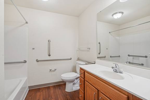 A white toilet sits in a bathroom next to a sink and a shower.