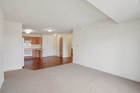 A large empty room with a kitchen area in the background.
