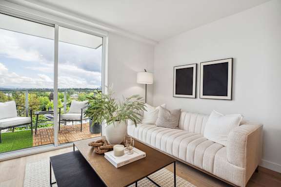 A living room with a couch, a table, and a view of the outdoors.