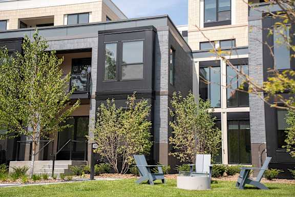 A modern building with a glass facade and a green lawn in front.