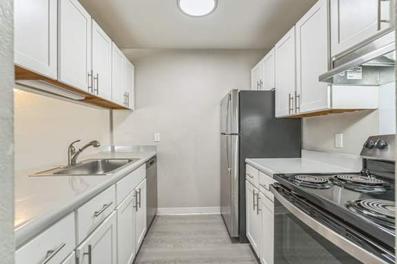 A kitchen with white cabinets and a black refrigerator.