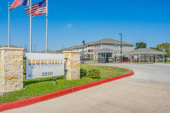 The entrance to Summerdale Apartments is marked by a large sign and flags.