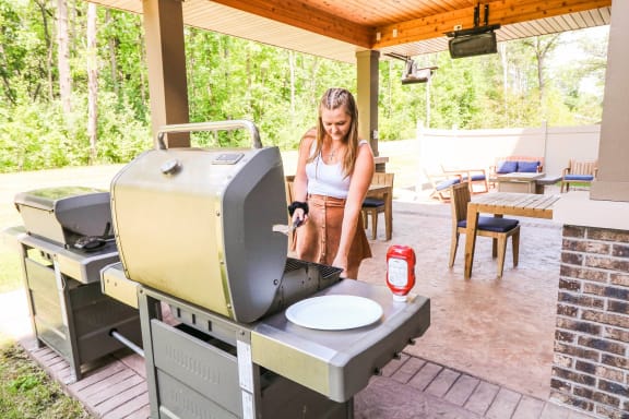 Woman barbecuing on an outdoor grill on a patio