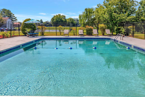 a swimming pool with two chairs and a fence around it