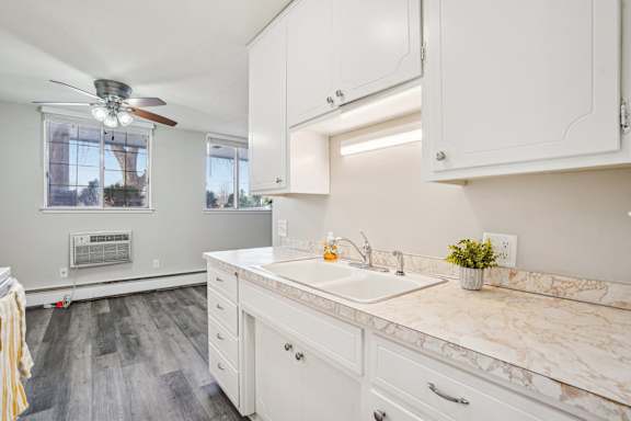 A kitchen with white cabinets and a marble countertop.