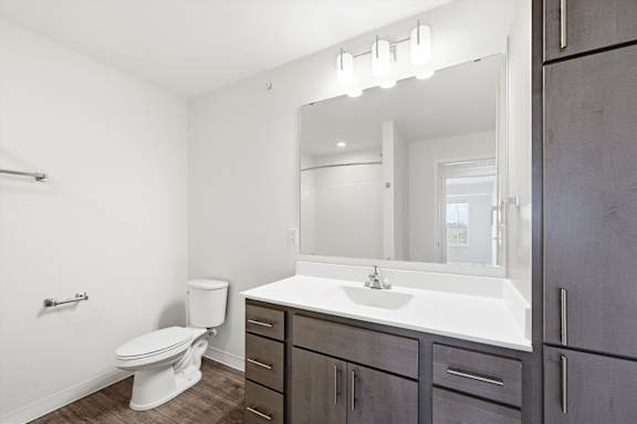 A bathroom with a white toilet, sink, and mirror.