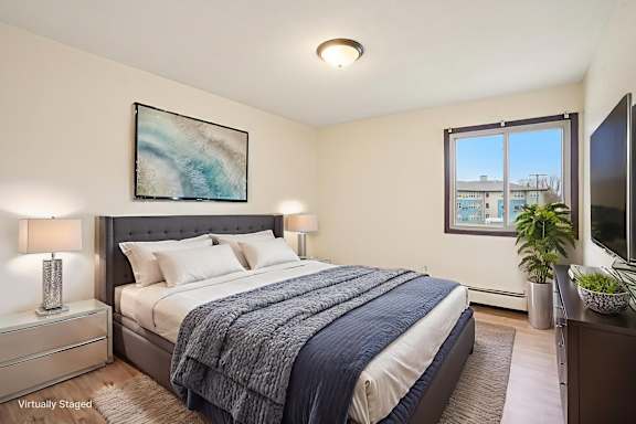 A bedroom with a bed, nightstand, and a painting on the wall.