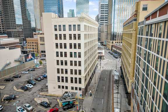 A parking lot with cars and a street in front of a white building.