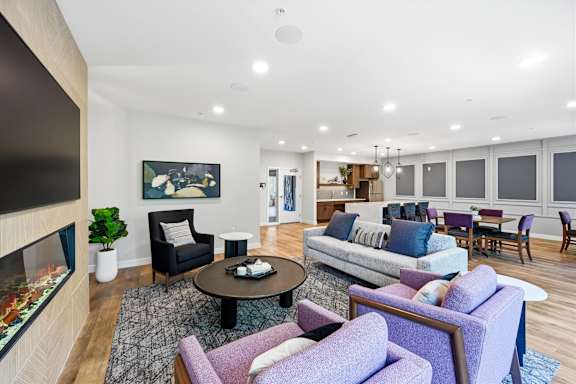 A living room with a purple couch and a fireplace.