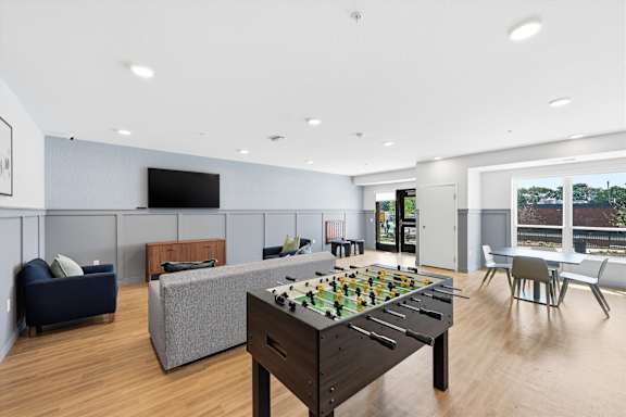 A game room with a foosball table and a couch.
