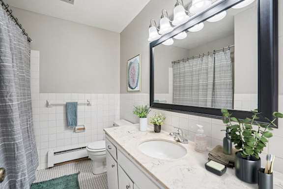 A bathroom with a white sink, toilet, and a mirror above the sink.