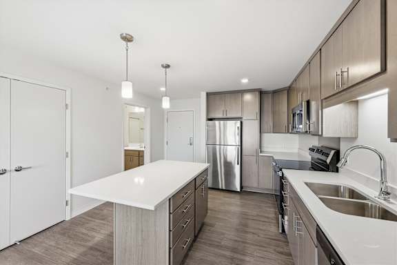 A modern kitchen with a white countertop and stainless steel appliances.