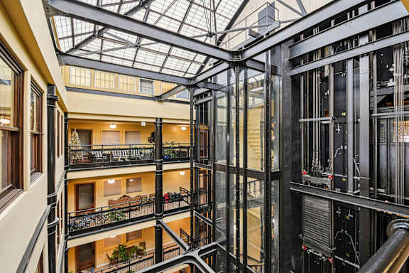 A view of a multi-level atrium with a glass ceiling and metal framing.