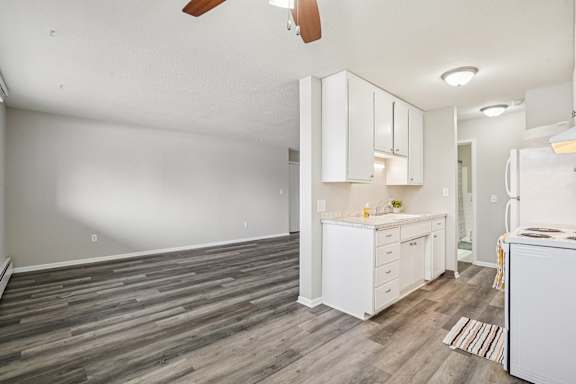 A kitchen with white cabinets and a wooden floor.
