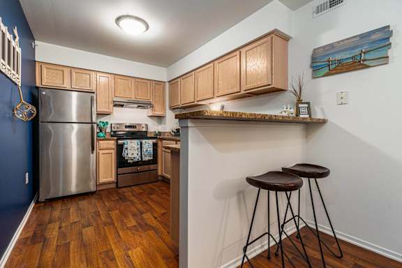 a kitchen with a bar with stools and a stainless steel refrigerator