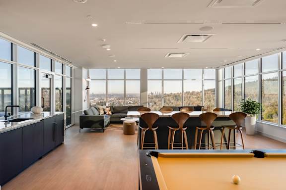 A billiard table is in the middle of a room with a view of the city.
