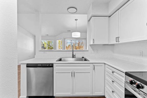 A modern kitchen with white cabinets and stainless steel appliances.