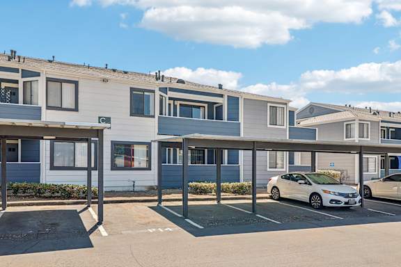 A row of townhouses with cars parked in front.
