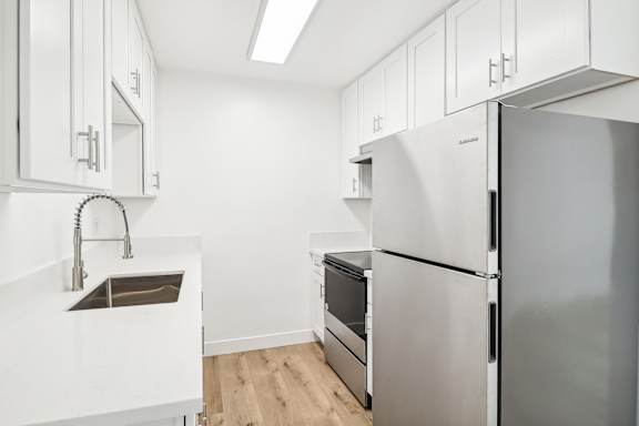 A kitchen with white cabinets and a stainless steel refrigerator.