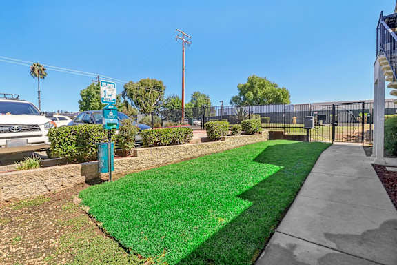 A green sign is on a post in front of a grassy area.
