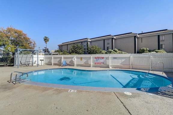 A pool surrounded by a fence with a building in the background.