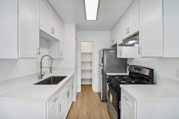 A kitchen with white cabinets and black appliances.
