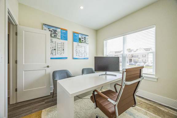 A room with a white desk and brown chairs.