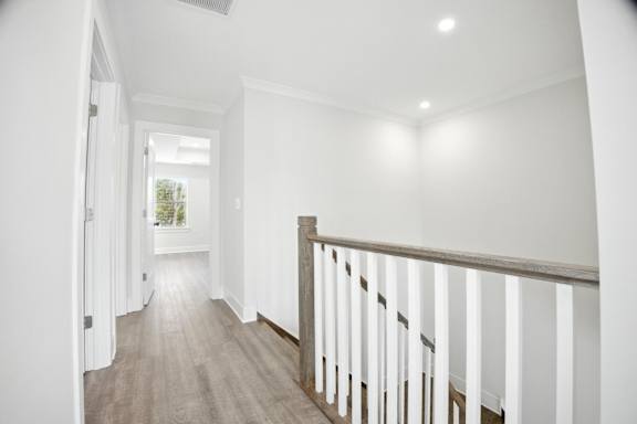 A long hallway with a white railing and wooden floor.