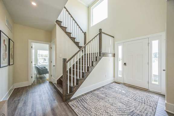 A hallway with a staircase and a rug on the floor.