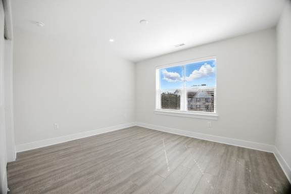 A room with a window showing a view of a building and a blue sky with clouds.