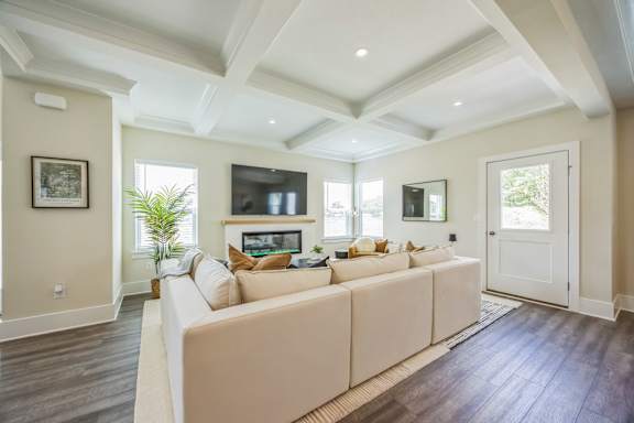 A living room with a white couch and a flat screen TV mounted on the wall.