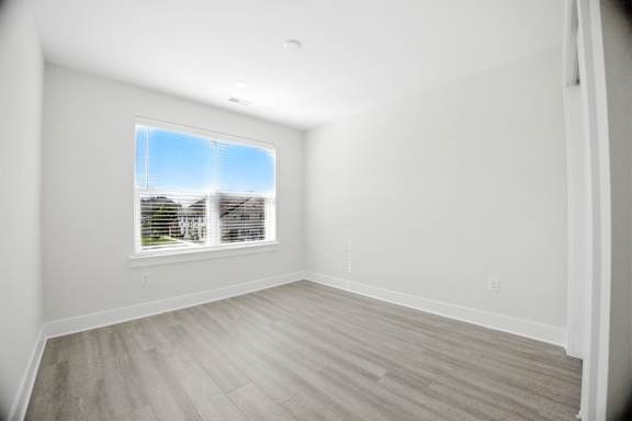 A room with a window and wooden flooring.