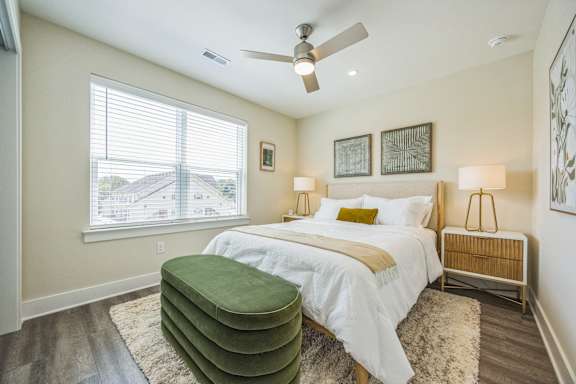 A bedroom with a large bed and a green ottoman.