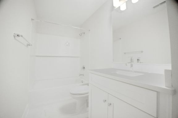 A white bathroom with a toilet, sink and mirror.