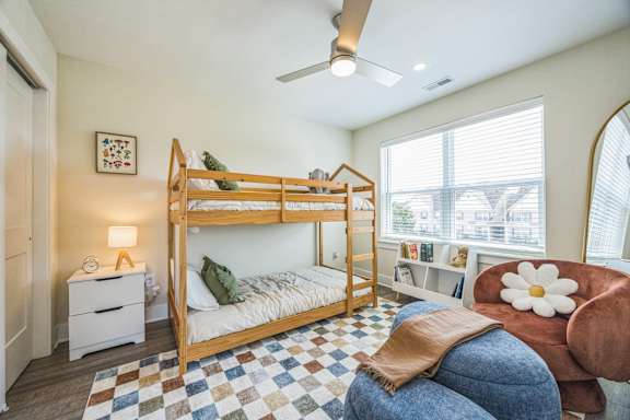 A bedroom with a bed, chair, and a ceiling fan.