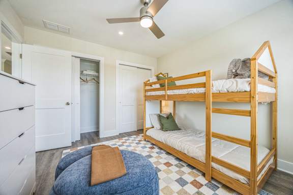 A bedroom with a bunk bed and a ceiling fan.