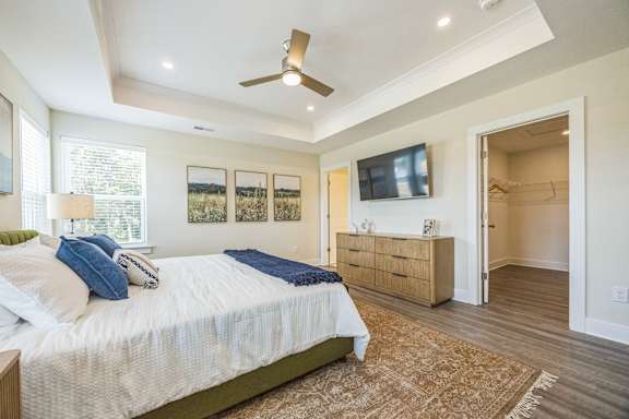 A bedroom with a bed, dresser, and ceiling fan.
