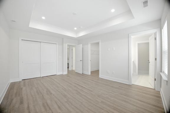 A spacious room with white walls and wooden flooring.