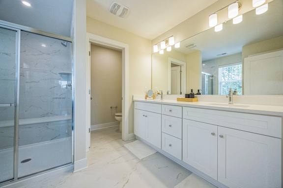 A bathroom with a marble floor and white cabinets.