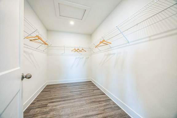 A hallway with a door on the left and clothes hangers on the wall.