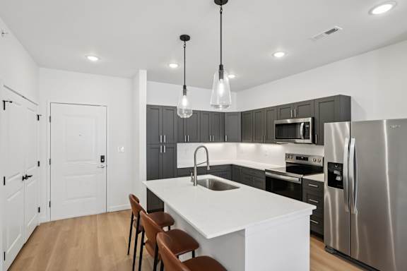 A kitchen with a white island and wooden chairs.