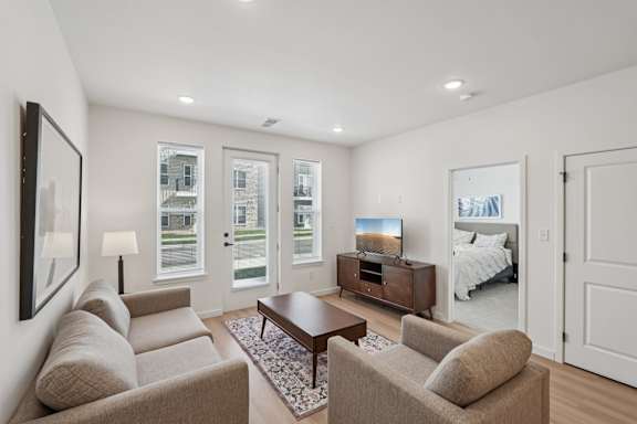A well-lit living room with a couch, coffee table, and television.