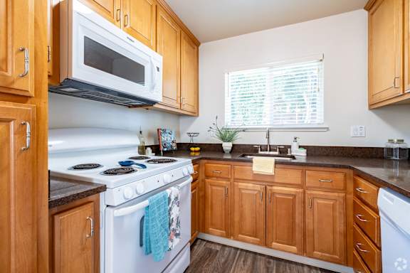 a kitchen with a stove and microwave and wooden cabinets