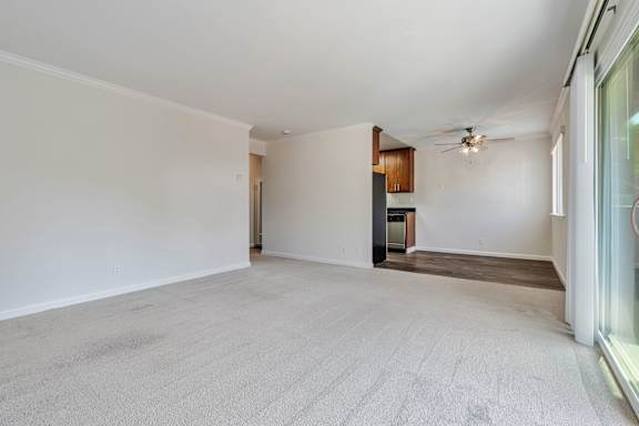 A spacious room with a ceiling fan and a door leading to another room.