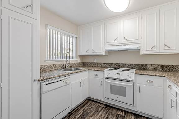 A white kitchen with a sink, stove, and oven.