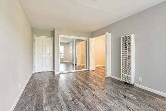 A room with a carpeted floor and a window with blinds.