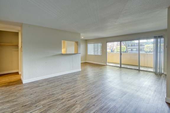 an empty living room with wood flooring and sliding glass doors