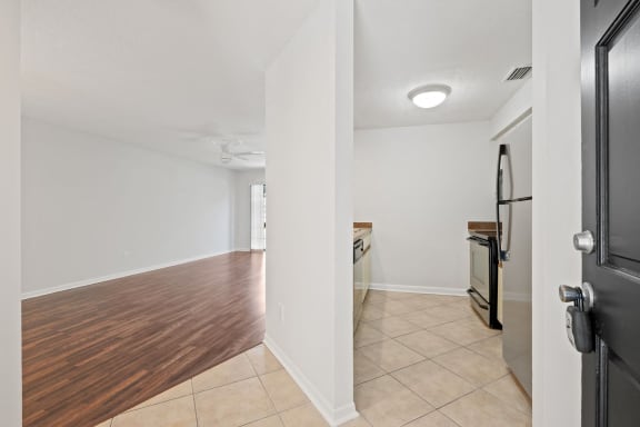 a renovated living room and kitchen with wood flooring and white walls